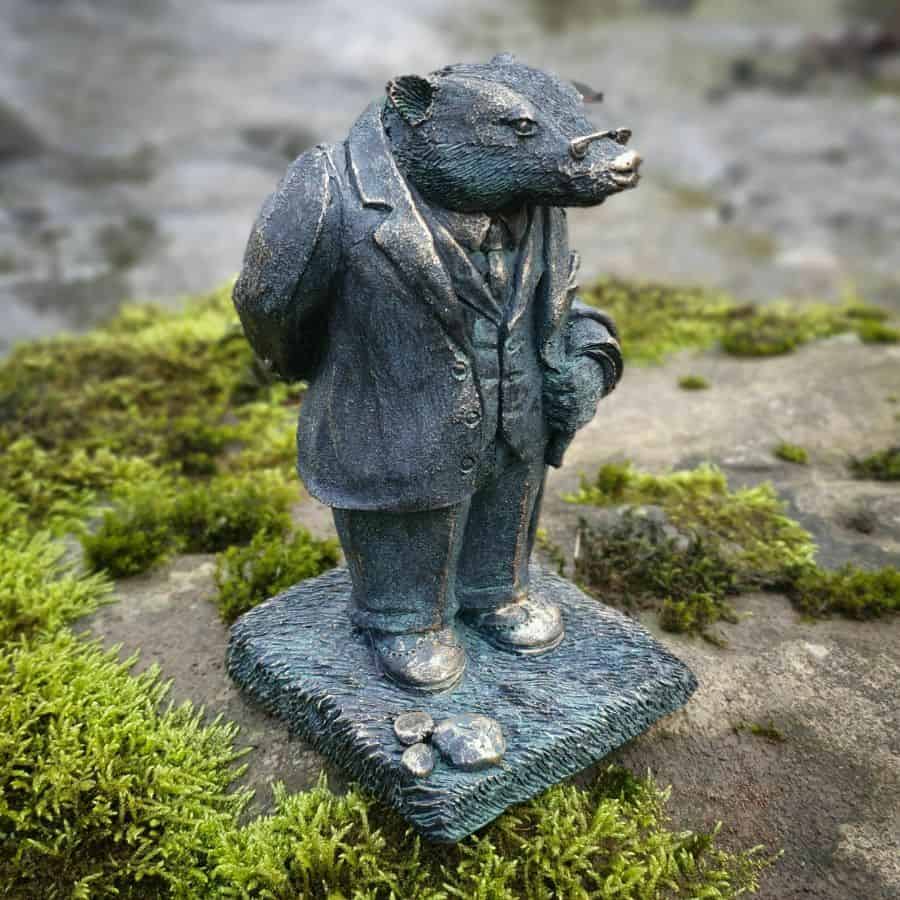 Badger from The Wind in the Willows, featuring spectacles and jacket. Situated amongst the moss of a British garden