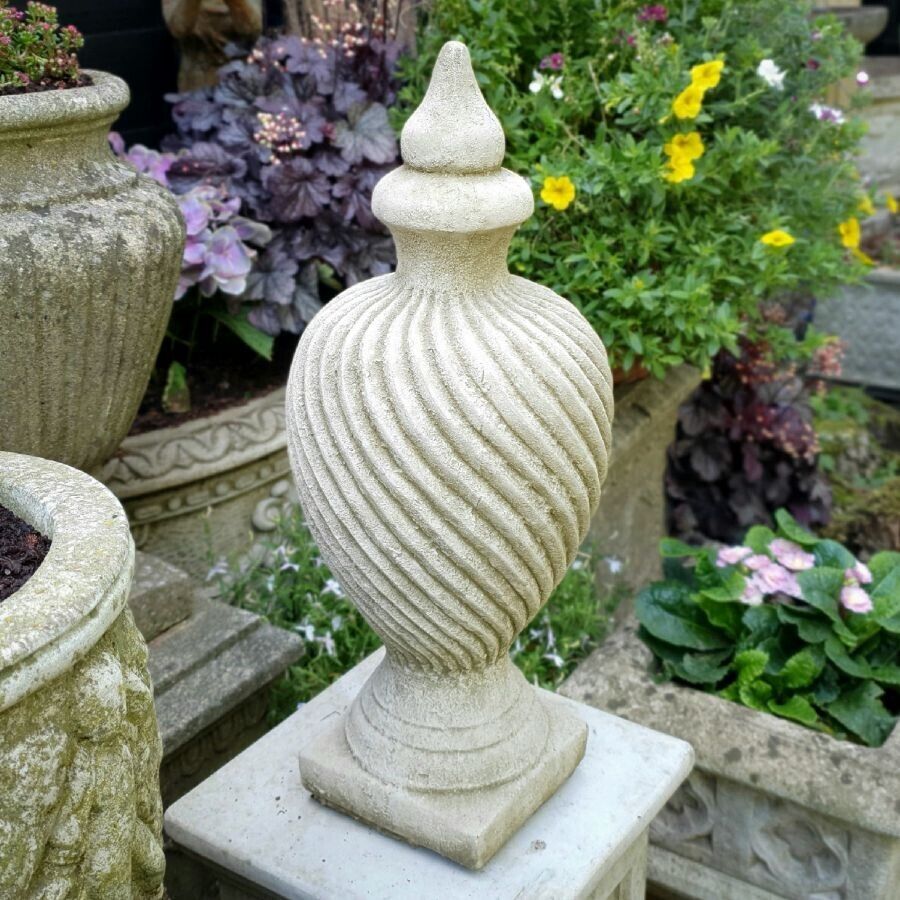 A beautiful curving Finial with pointed top. Situated in a British garden surrounded by beautiful, colourful flowers