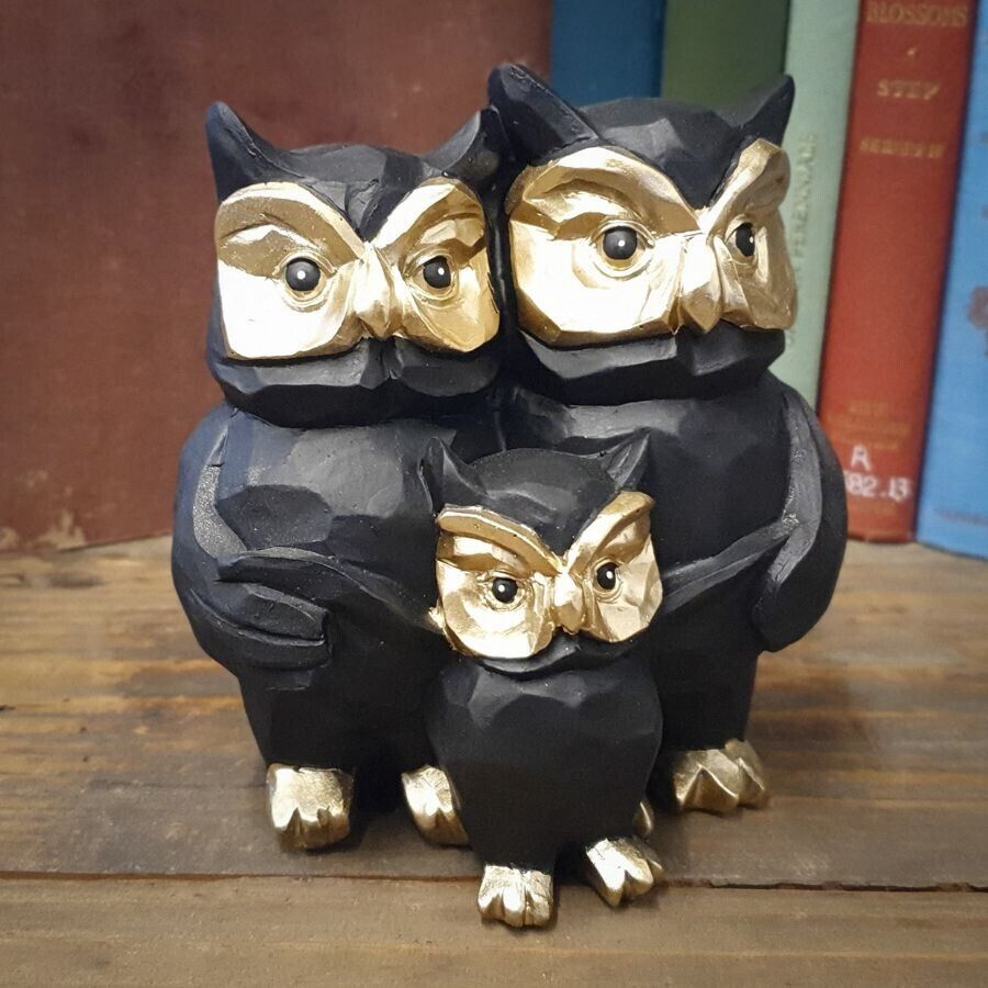 A family of three owls with golden faces and black bodies