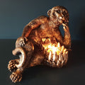 An ape laying on their side ponderously with tealight holder by their torso