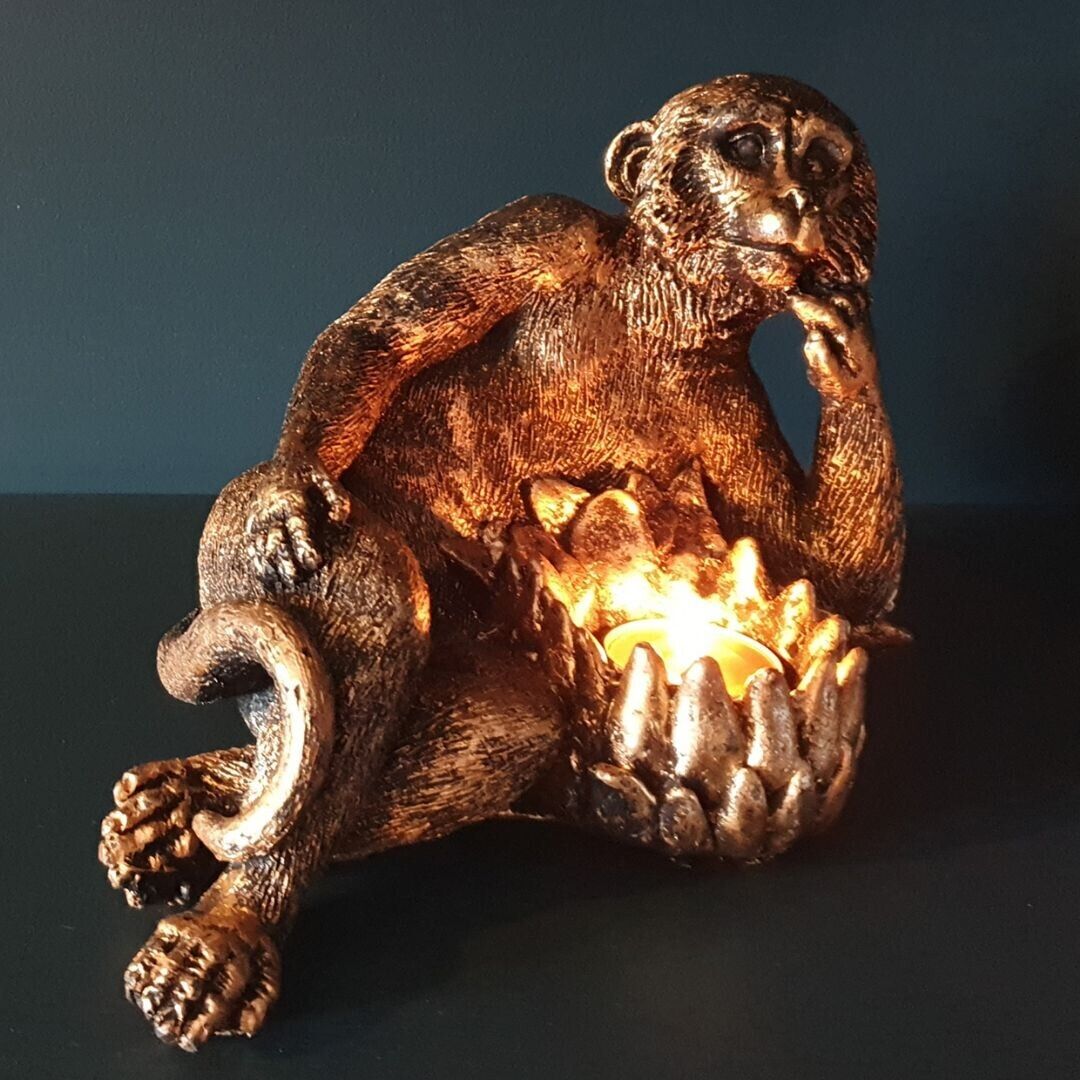 An ape laying on their side ponderously with tealight holder by their torso