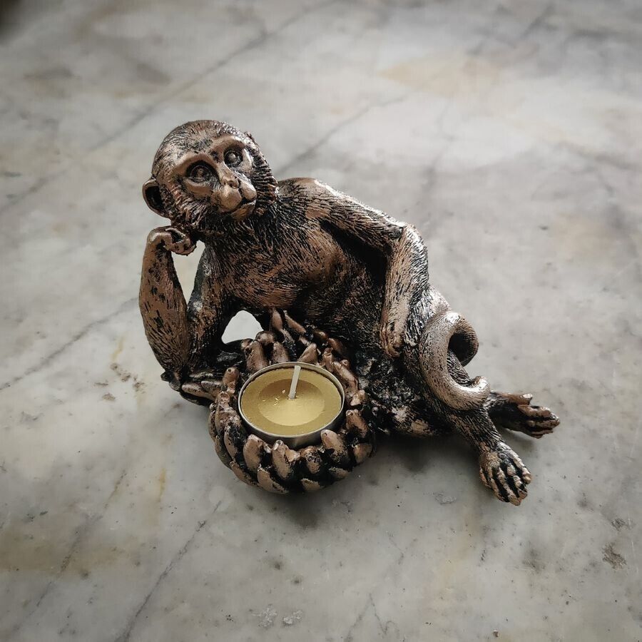 A monkey laying side on with a tealight made of bananas.