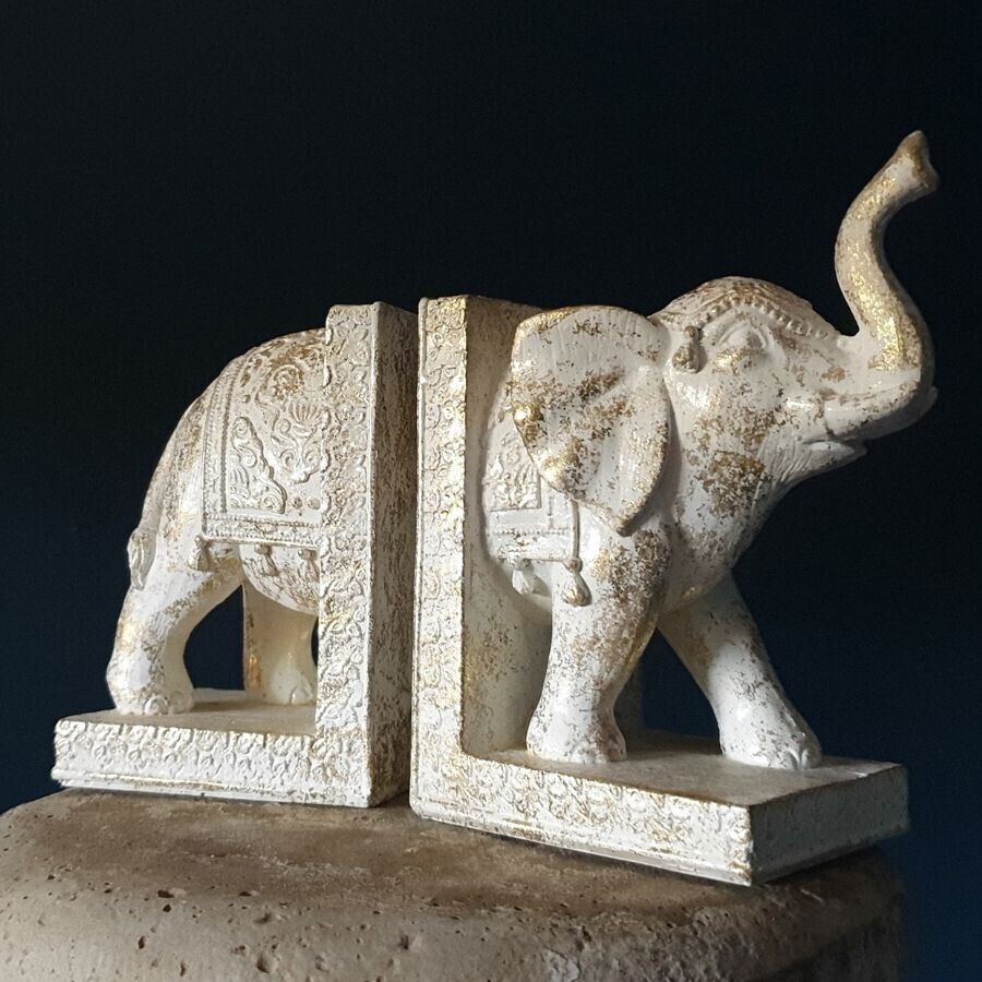 An elephant in half, with each half standing on a book. Intricate gold detailing