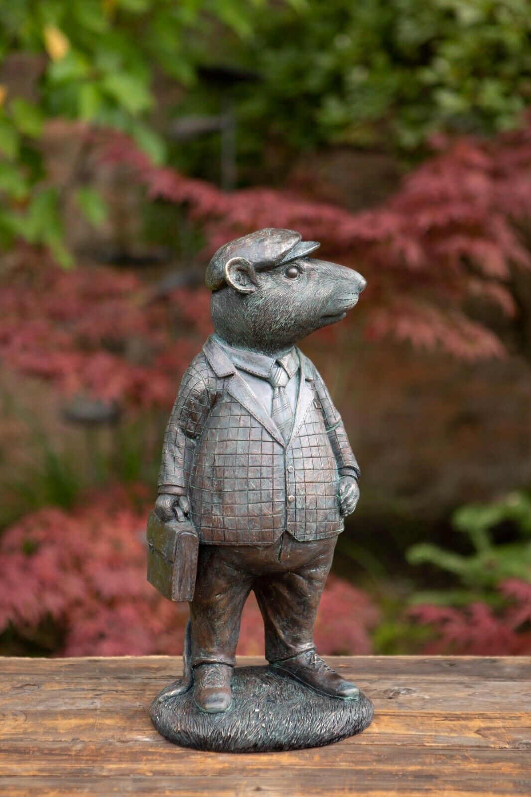 A Mr Mouse Figure with sports jacket and briefcase. Situated in a British garden with red foliage in the background