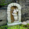 A tiny mouse poking out of their front door in full colour. Situated in the grass of a British garden with wooden log in the background