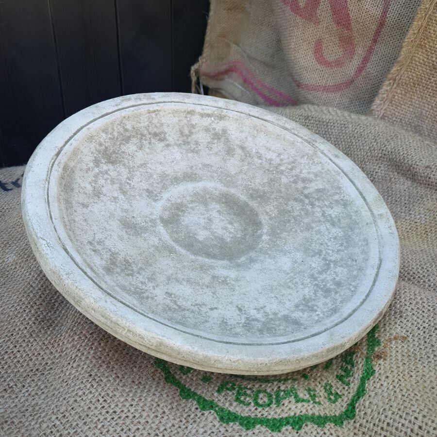 The top half of a birdbath feeder of grey stone. Situated on the hessian sack of a photography studio