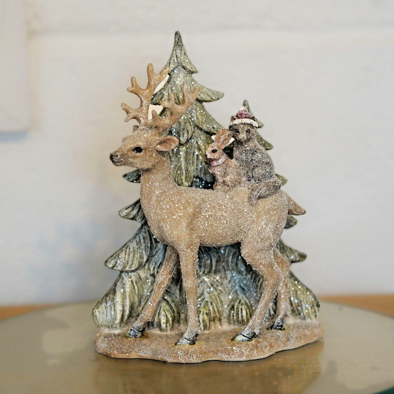 A reindeer of brown colour with woodland critters on back walking amongst the Christmas trees. Situated on the dinner table of a British home