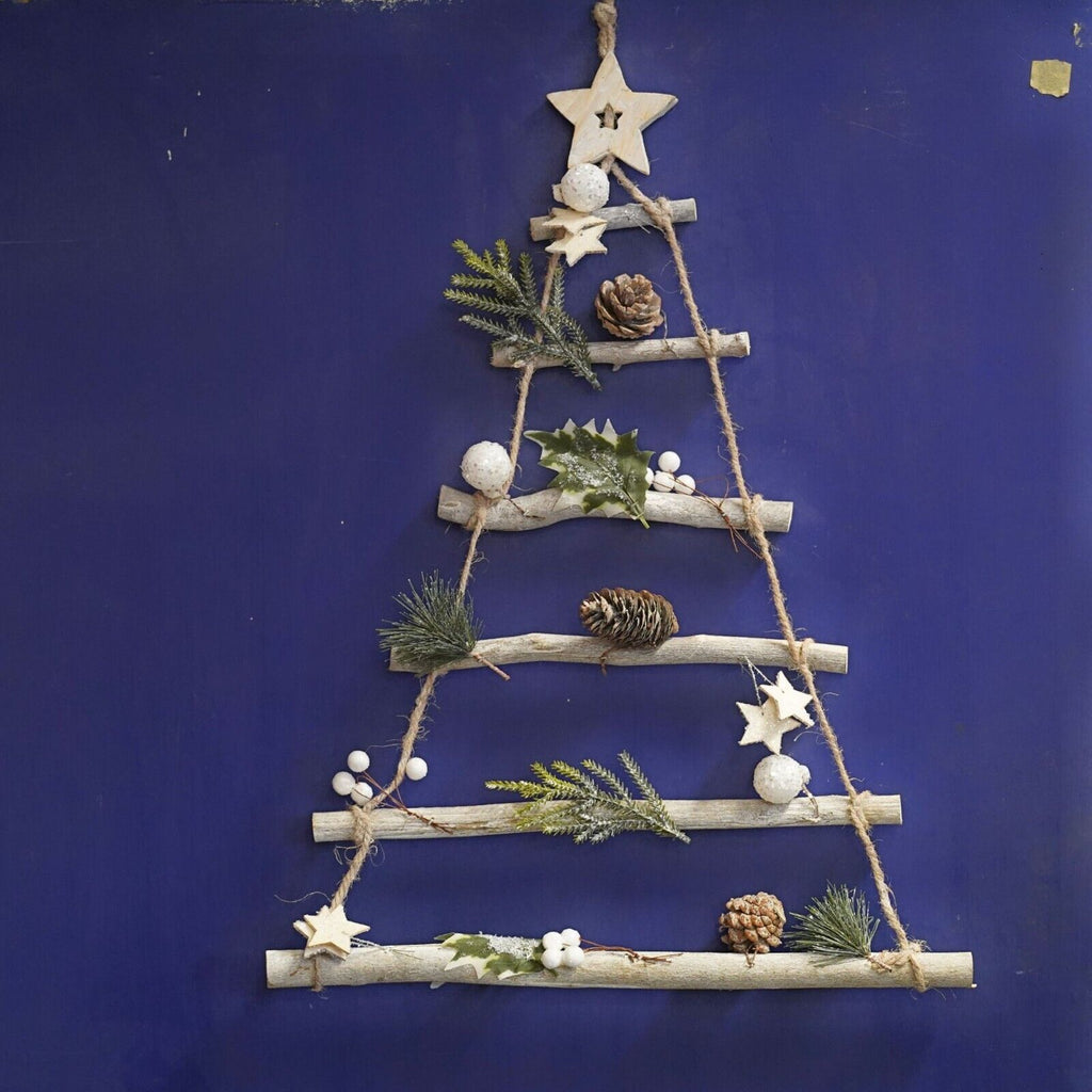 Wooden twigs assembled to resemble a christmas tree, attached with strings and adorned with pinecones and forest leaves with a wooden star on top