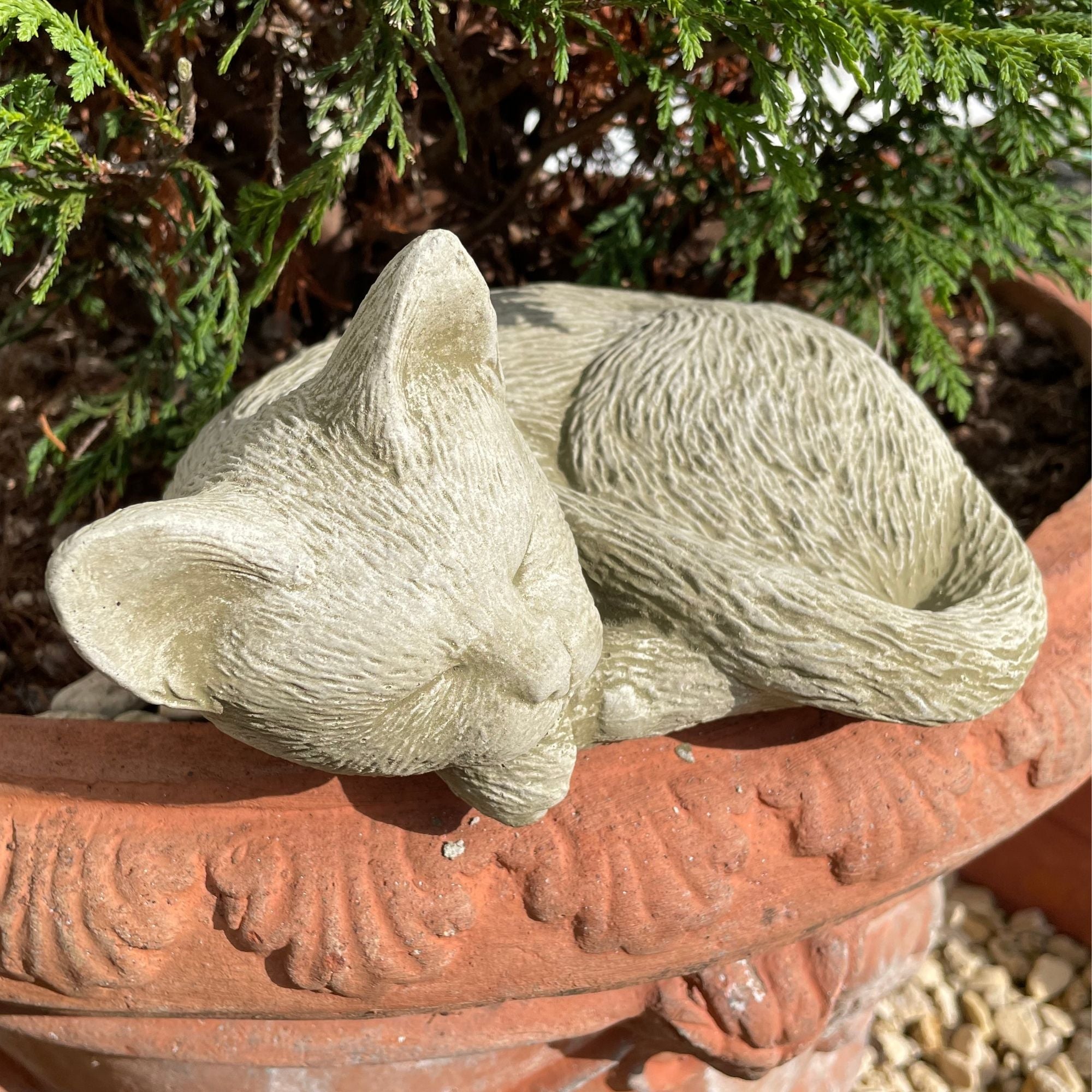 A stone statue of a cat used as a garden ornament.