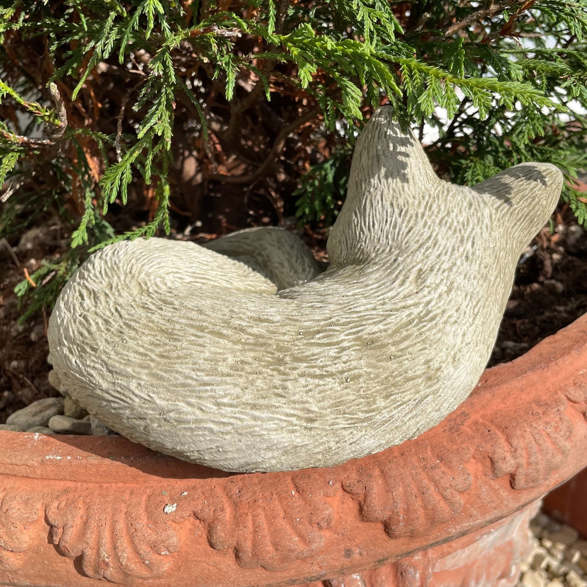 A stone statue of a cat used as a garden ornament.
