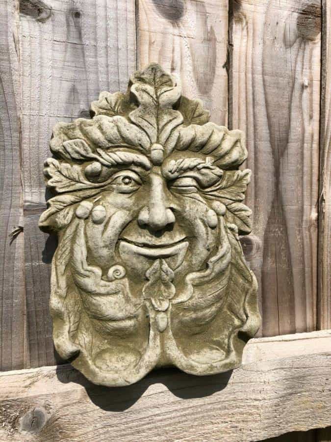 A charismatically winking greenman face from folklore situated on garden fence in Britain