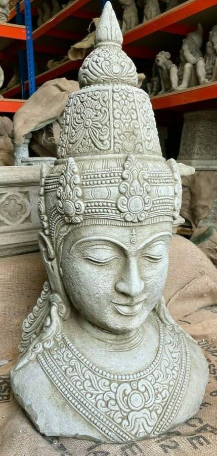 A large buddha head in Thai style with intricately detailed headwear. Situated in the warehouse of a British statuary