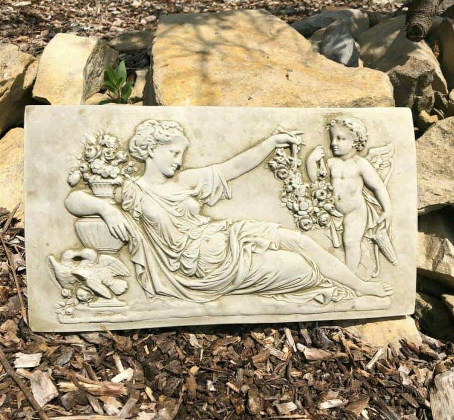 A laying roman lady featured on a rectangular hanging plaque. Situated on the ground of a british garden