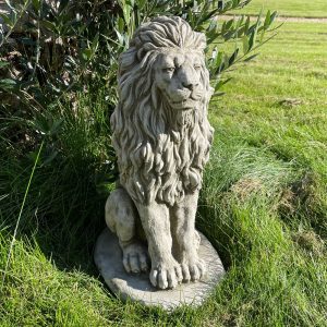 A stone lion statue in use as a garden ornament.