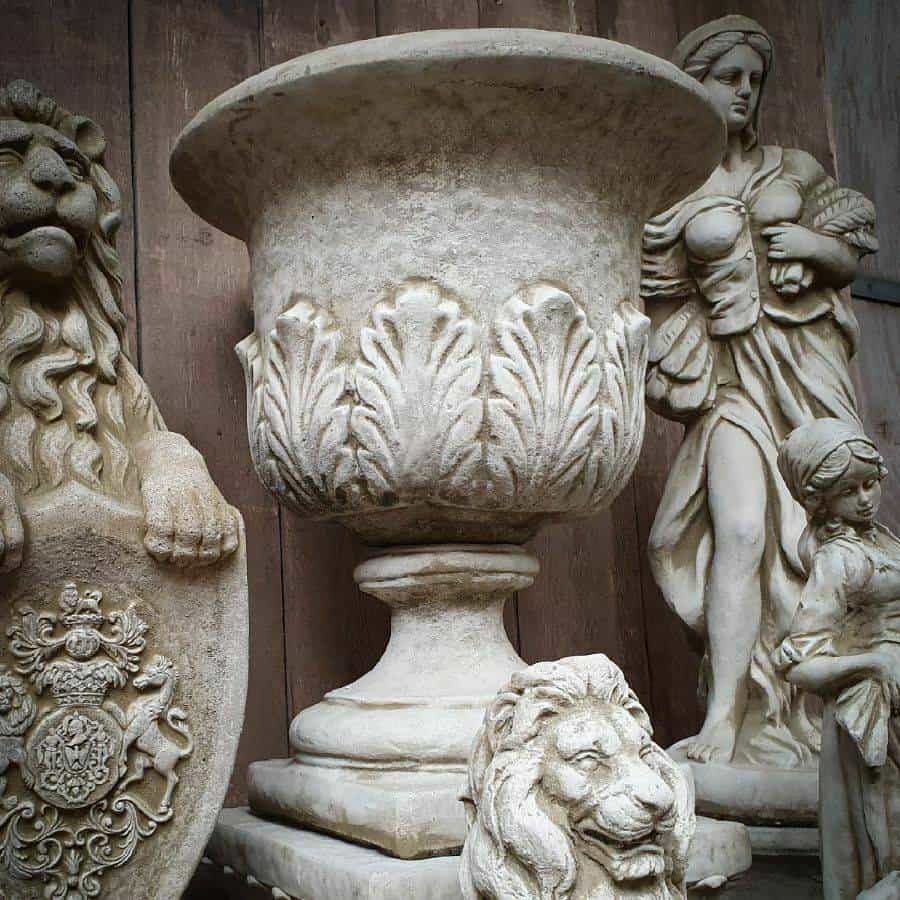 A large urn with leaf pattern. Situated on the stone plinth of a British statuary, surrounded by classical style statues