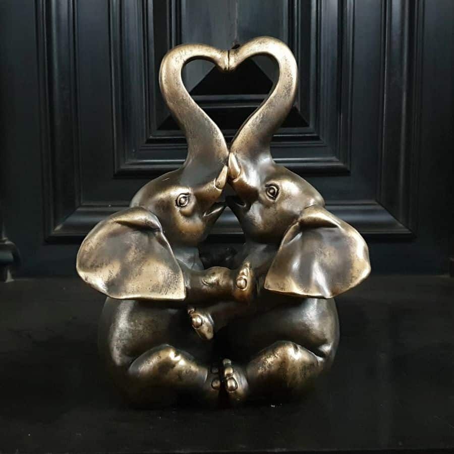Two elephants sat facing each other, with their two trunks extended to form two sides of a classic heart shape. Situated on the black marble floor of a British home