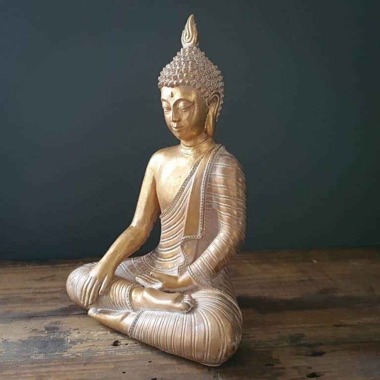 A buddha of gold finish with legs crossed, sitting peacefully in a British home.