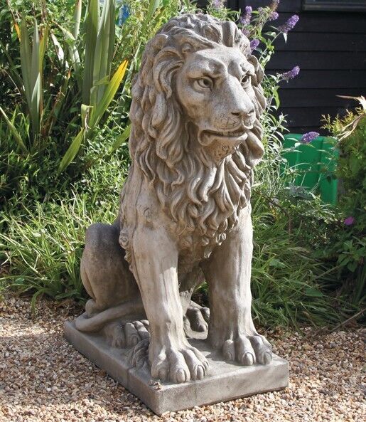 a colossal stone lion sitting and snarling majestically and powerfully with long flowing mane and protective eyes. Situated amongst the flora of a British Garden
