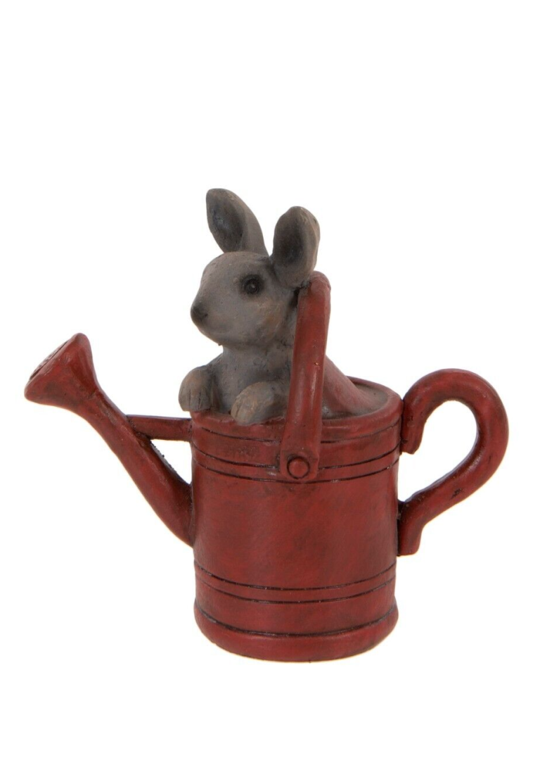 A little rabbit with a curious look sitting in a red watering can