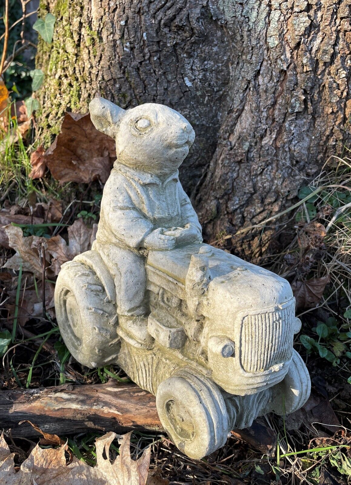 A rabbit with waist-coat riding an antique style tractor. Situated in a British garden in front of a tree.