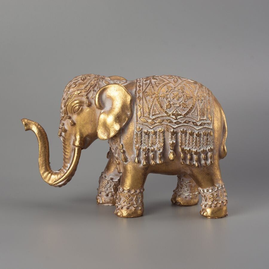 A golden elephant adorned with indian style decoration with trunk raised.