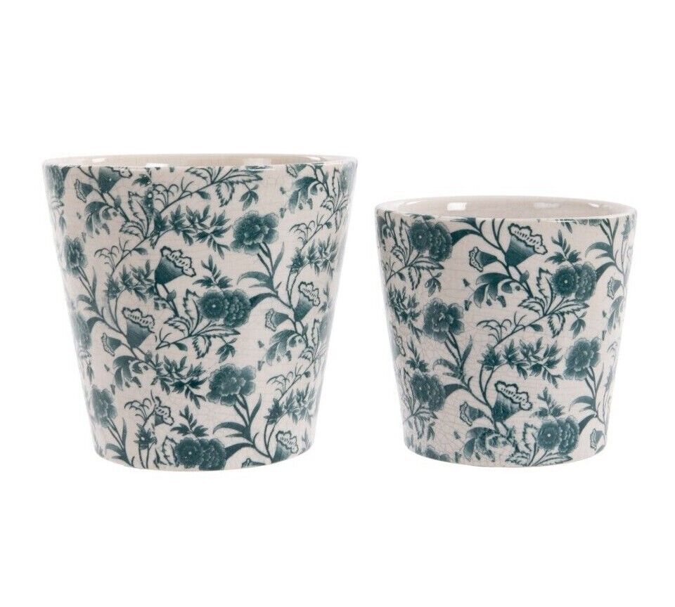 Two round ceramic pots of white finish with green floral pattern of intricate design. Situated on a white studio background