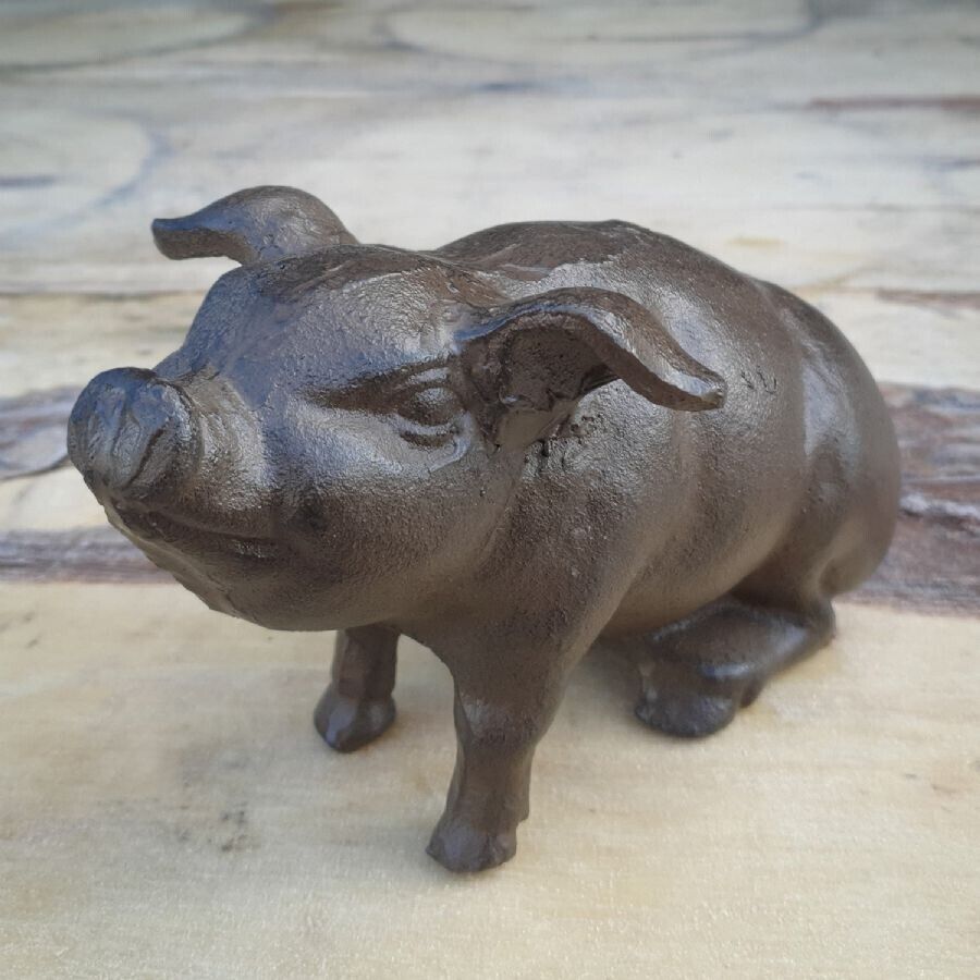 A cast iron pig of dark brown finish sitting on the marble floor of a British home